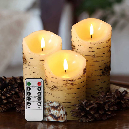 Three melted top birch pattern flameless pillar candles with a ten-button remote. There are brown plants and shells on the side for decoration