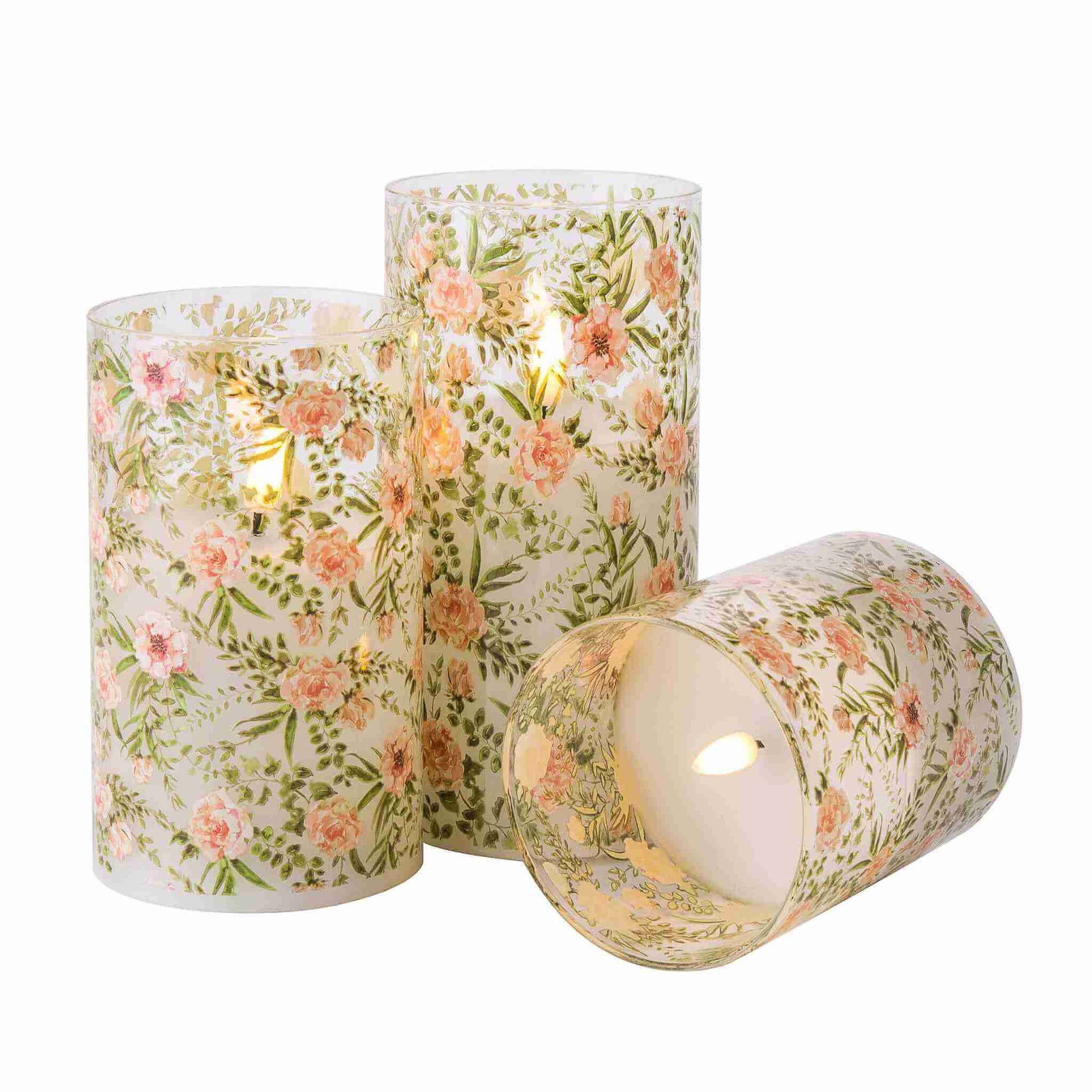 Three lit eywamage floral glass flameless candles, one of which is placed sideways