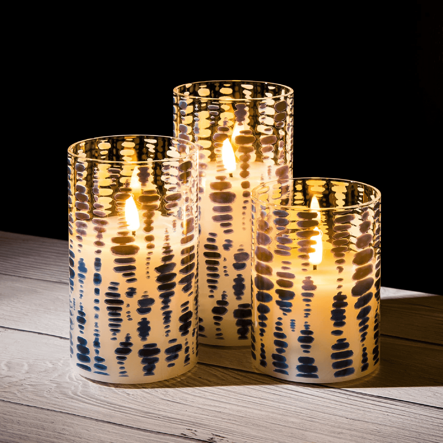 Three blue dots glass flameless candles are lit and placed on a wooden table