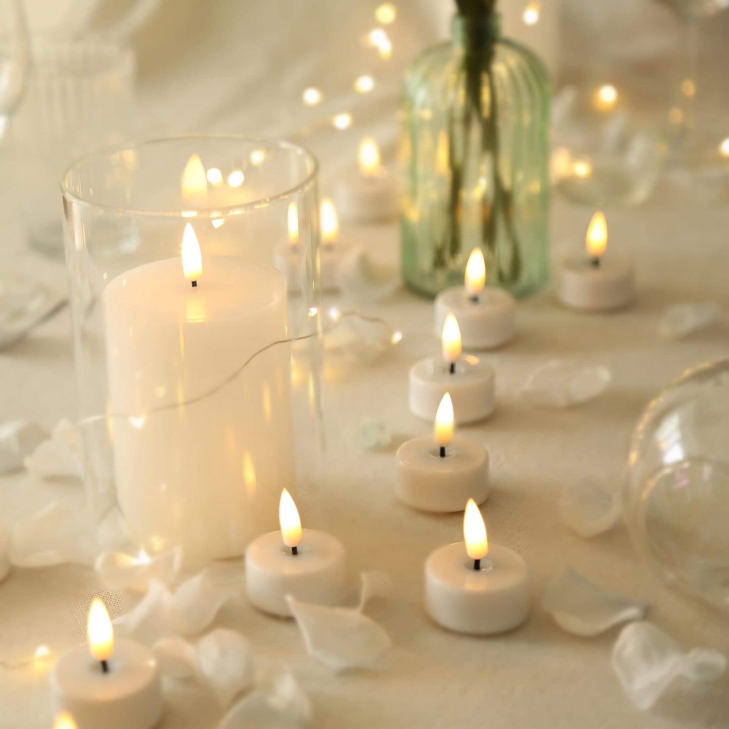 The table is decorated with glass bottles, flower petals and some eywamage white flameless flat top candles and led tedlights