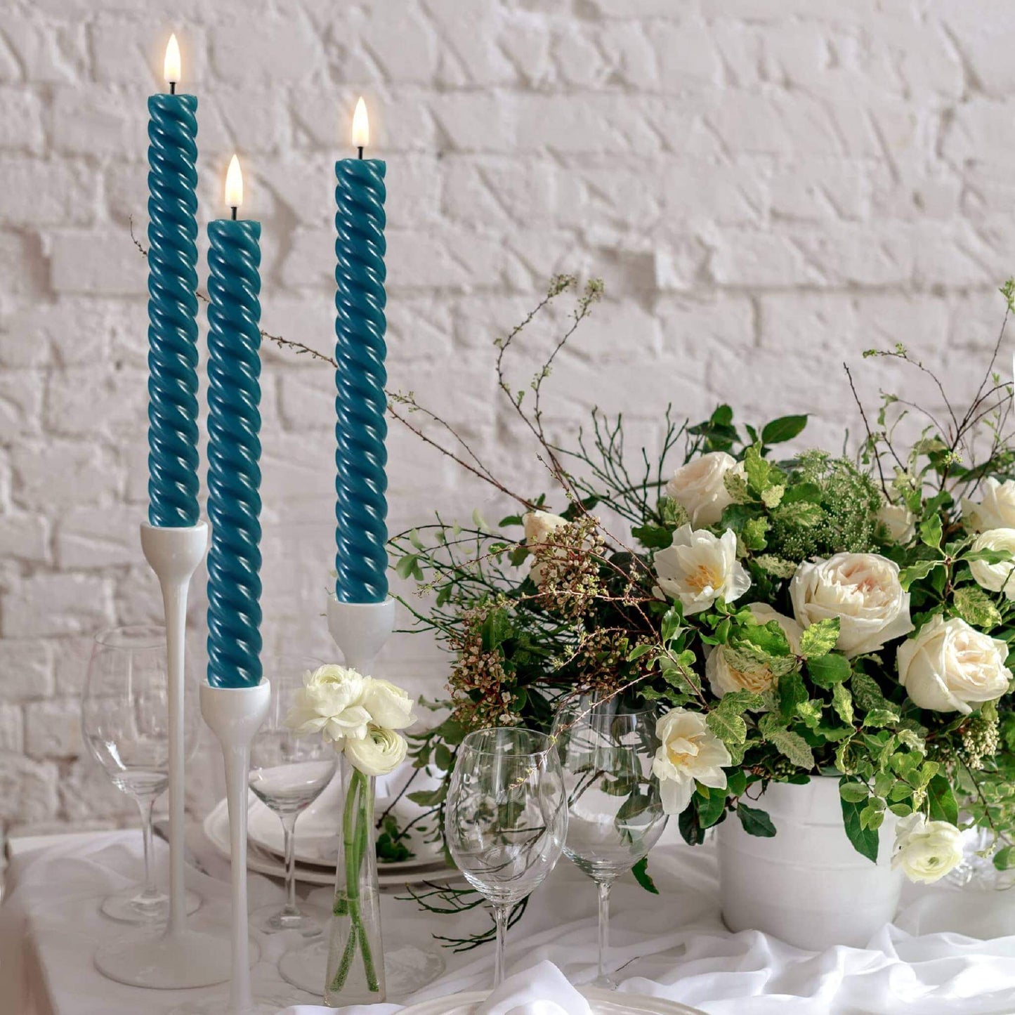 Well-decorated dining table, white tablecloth, exquisite wine glasses and cutlery, a beautiful pot of flowers and three eywamage blue spiral flameless taper candles