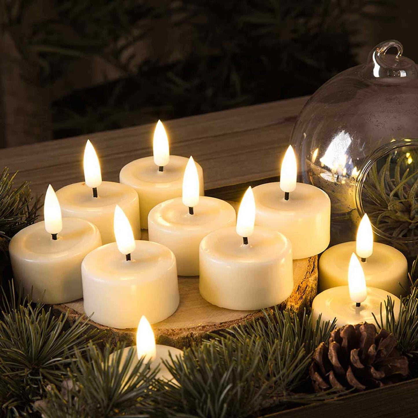 10 flameless tea light candles are lit on wooden stakes surrounded by many needle-like greenery and a glass shade